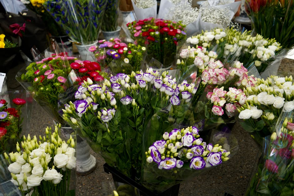 A variety of fresh floral bouquets on display at a flower shop, featuring an assortment of colorful flowers including purple and white lisianthus, pink carnations, white roses, and small pink and purp
